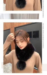 Detail of a black faux fur scarf featuring a large plush ball and silky ribbon tie
