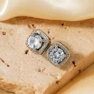 Macro shot of silver square halo stud earrings with brilliant zircon stones and fine claw setting