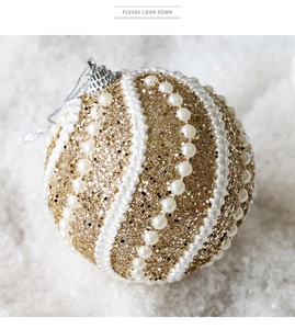 Détail d'une boule de Noël dorée de 8cm avec paillettes, perles blanches et cordon d'attache