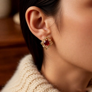 Gros plan de boucles d'oreilles vintage avec zircon rouge sur un mannequin en tricot
