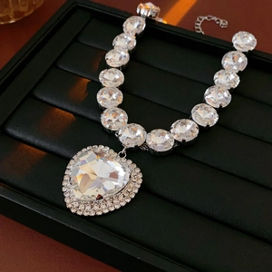Detail of a luxury heart pendant necklace with shimmering crystals on a jewelry tray