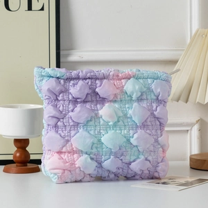 Macro detail of quilted bubble fabric showing pastel purple and pink tie-dye cosmetic bag