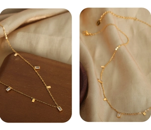 Detail of gold titanium steel necklace featuring square zircon and small metal charms