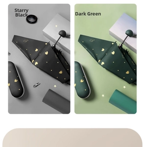 Detailed view of portable sun umbrellas in black and green with gold heart patterns