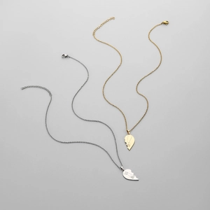 Detail of heart puzzle pendants with hand-holding engraving for couples in gold and silver