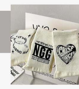 Detailed knit of three cream cotton socks featuring black typographic designs and hearts