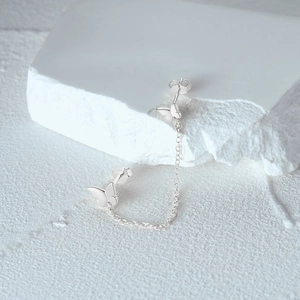 Detailed macro shot of S925 sterling silver butterfly chain earrings on stone