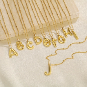 Detailed close-up of gold-plated alphabet necklaces A-J on a textured background