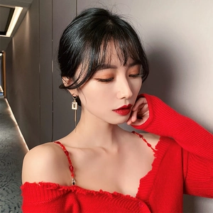 Detail of elegant gold tassel earrings worn by a model in a red cardigan