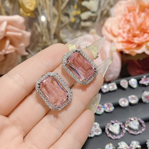 Macro detail of emerald-cut pink gemstone earrings with sparkling halo and silver setting
