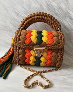 Detail of handmade crochet handbag featuring colorful V-pattern stripes and gold chain strap