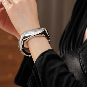 Close-up of polished silver irregular metal cuff bracelet on a model's wrist