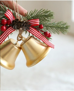 Nahaufnahme von Weihnachtsanhänger mit goldener Glocke, roter Schleife und Tannennadeln