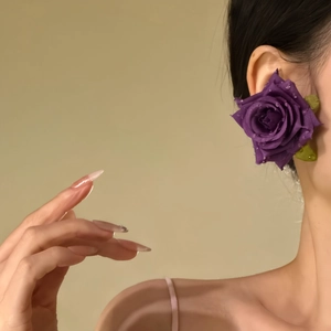 Macro view of elegant purple fabric rose earring on model's ear with high detail and soft lighting