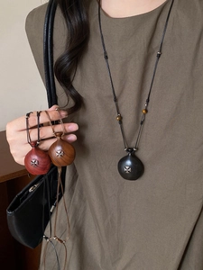 Détail du pendentif en bois en forme de bouteille avec croix argentée et cordon réglable