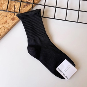 Close-up of black ribbed knit cotton sock with a white brand label on a white background