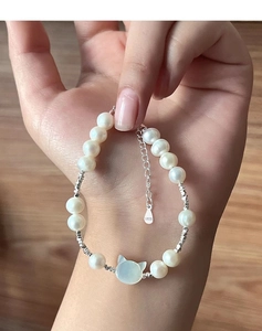 Macro shot of S925 sterling silver freshwater pearl bracelet with cat-shaped blue pendant