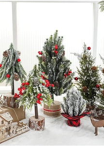 Close-up of mini snowy Christmas trees with red berries and rustic wooden bases