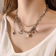 Detail of layered silver necklace with pearl pendant, heart charm and signature logo