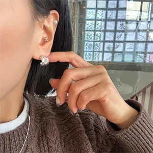 Detailed view of silver C-shaped earrings with opal stone inlay on model's ear