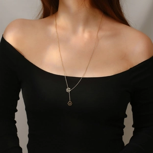 Detail of a gold Y-shaped necklace with dog paw pendants worn by a fashion model