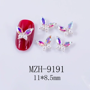 Macro shot of 3D aurora butterfly nail gems with pearls on a deep red nail tip