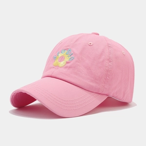 Close-up of pink baseball cap featuring detailed floral and STUDIO embroidery on fabric