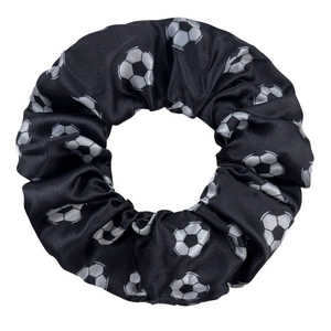 Détail d'un chouchou élastique noir avec des motifs de ballons de football imprimés