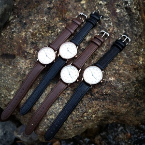 Quartz watches with leather straps and large numeric dials displayed on a natural rock