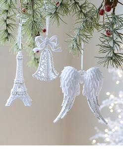 Detail of white Christmas ornaments with glitter including Eiffel tower, bell and wings