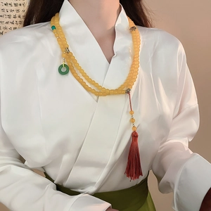 Détail du collier de perles avec pendentif anneau de jade vert et long gland en soie rouge