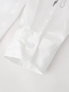 Detail of white satin sleeve cuff featuring silver bead embroidery and a white button
