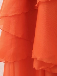 Vue détaillée du tissu en mousseline orange avec des volants superposés sur la robe