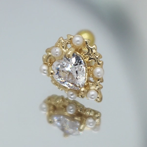 Dettaglio macro dell'orecchino a cuore dorato con zircone e perle incastonate