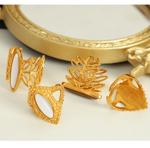 Detail of four gold vintage rings with white gemstone inlays on a golden mirror background