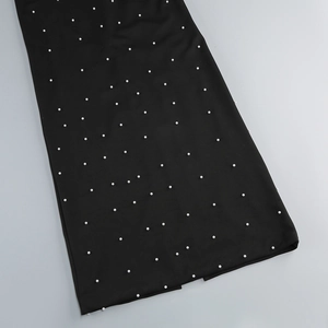 Gros plan de perles blanches élégantes méticuleusement fixées sur un tissu noir mat