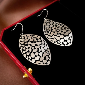 Detail view of silver hollow leaf tassel earrings displayed on a red luxury jewelry box