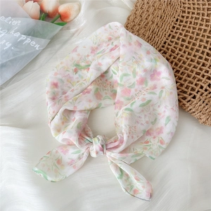 Detail of floral chiffon scarf with letter print styled with tulip bouquet and woven bag