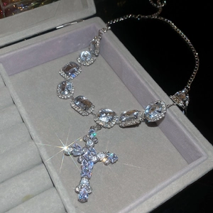 Macro shot of silver cross pendant necklace with blue stones in a velvet jewelry box