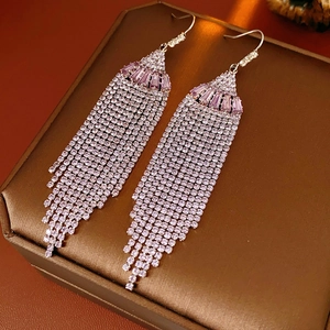 Detail view of silver tassel earrings featuring purple stones on a jewelry box