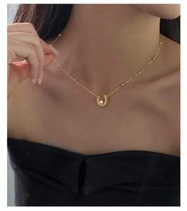 Detailed view of S925 silver pearl necklace with horseshoe pendant on a model