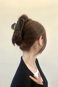 Detail of matte black geometric hair claw clip on dark brown hair in a chic updo