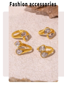Detail of 18k gold plated open rings with double pear-cut zircons on a textured stone surface