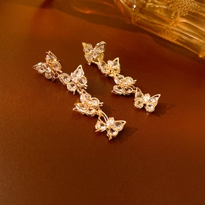 Detailed shot of long gold butterfly tassel earrings with sparkling zircon on leather