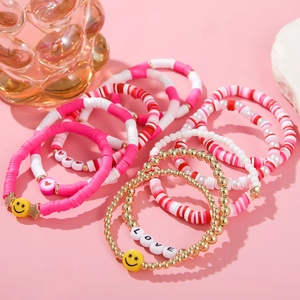 Detail view of pink and gold beaded bracelet layers with LOVE letters and heart charms