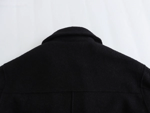 Gros plan détaillé du col à revers et de la couture d'épaule de la veste noire en tweed