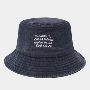 Close-up of white embroidered text on a navy blue washed cotton bucket hat