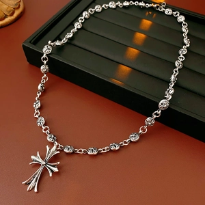Detail of silver vintage punk cross necklace on a black jewelry display stand