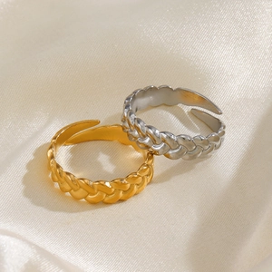 Twisted stainless steel open rings in gold and silver finish on soft silk background