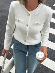 Detail of white knit cardigan featuring chic gold buttons and elegant crew neck design